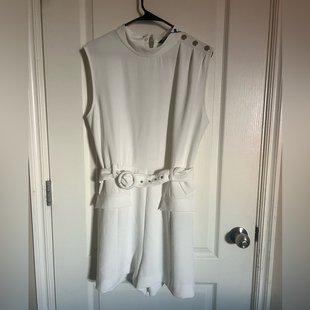 White romper with gold buttons on shoulder.